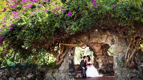 bride and groom under floral arch